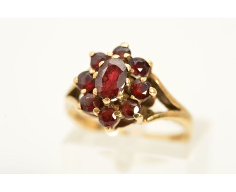 A 9CT GOLD GARNET CLUSTER RING, designed as a central oval garnet within a circular garnet surround, with 9ct hallmark, ring 