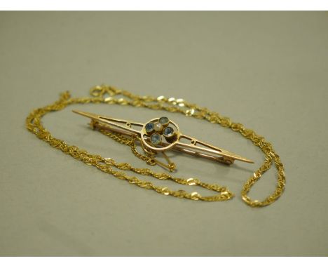 A GOLD BROOCH AND CHAIN, the early 20th century 15ct gold brooch with central open circular panel collet set with four circul