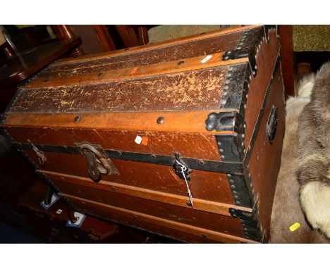 A VINTAGE WOODEN AND METAL BANDED DOMED TOPPED TRUNK