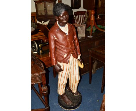 A GOLDSCHEIDER STYLE PLASTER FIGURE OF A YOUNG BOY STANDING, dressed as a street urchin on a circular base with extensive dam