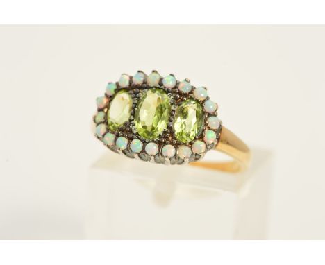 A PERIDOT AND OPAL DRESS RING, designed as three graduated oval peridots within a claw set, circular opal surround, ring size