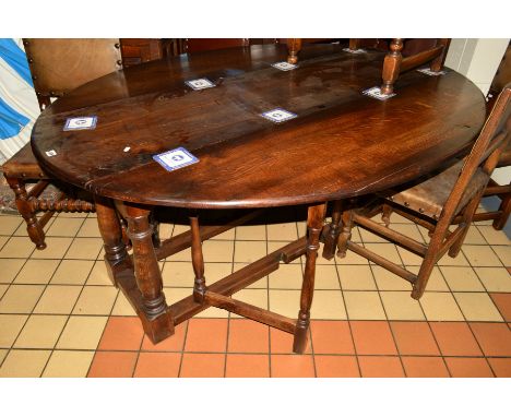 A REPRODUCTION GEORGE III STYLE OAK WAKE TABLE, the two rounded drop leaves to form an oval supported by four pivoting gate l