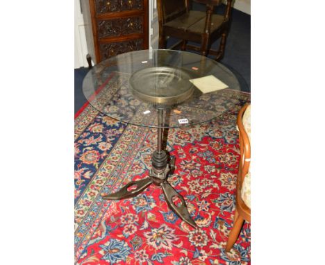 AN INDUSTRIAL CIRCULAR GLASS TOPPED TABLE, on a base formed from engine parts, diameter 64cm x height 71.5cm