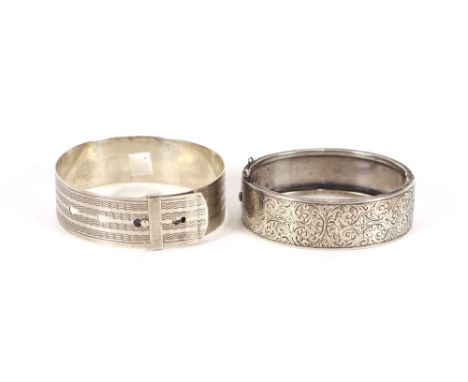 An unmarked white metal snap bangle with foliate decoration; and another bangle in the form of a belt, stamped Sterling
