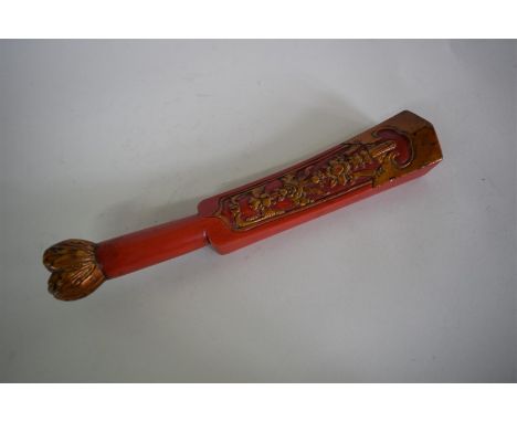 A Chinese red lacquered and parcel gilt carved wood wrist wrest or scroll weight, 33cm long.