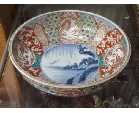 HANDPAINTED AND GILDED ORIENTAL CERAMIC BOWL, DECORATED WITH CHINESE MYTHICAL DRAGONS AND CENTRAL BLUE AND WHITE RIVER SCENE 