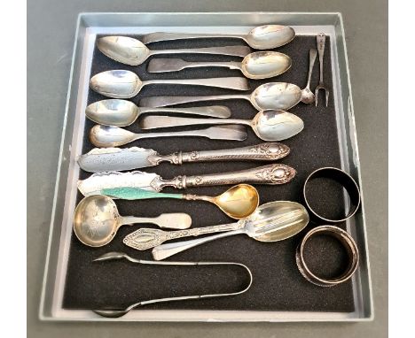 A collection of hallmarked silver items including various spoons, two master butter spreaders, two napkin rings, an enamel an