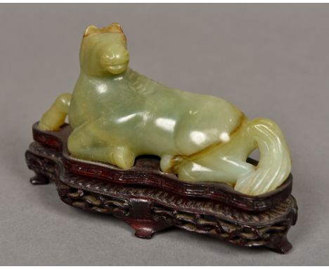 A Chinese carved green and russet jade horseModelled recumbent, mounted on a carved pierced plinth base.  13 cm long. 