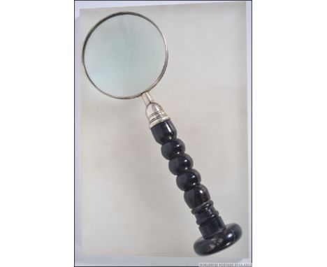 A vintage hand held magnifying glass having a silver plated framed glass raised on a bobbin turned horn handle. Measures 30cm