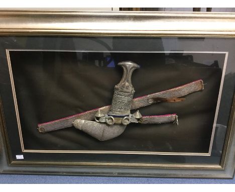 A Middle Eastern Jambya dagger with horn grip and white metal fittings complete with scabbard with white metal decoration and