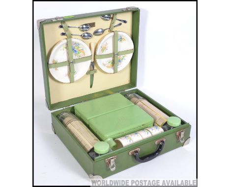 A vintage mid 20th century Brexton picnic hamper case in a green finish. Having a service for four people. Carry handle and l