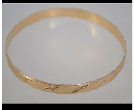 A hallmarked 9ct gold bangle with scalloped edges and diamond cut star engraving. Hallmarked London. Weight 10g