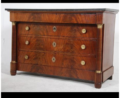 A 19th century French mahogany and black marble empire commode chest of drawers being raised on turned column supports with c