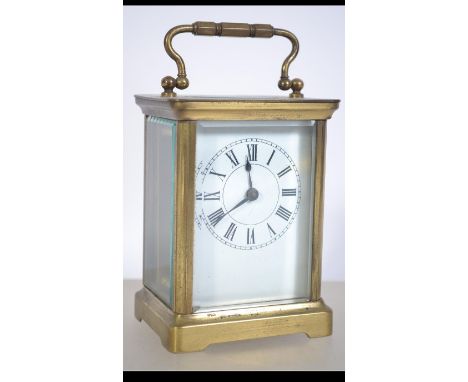 An early 20th century brass carriage clock complete with the key having enamel face with faceted hands and roman numeral chap