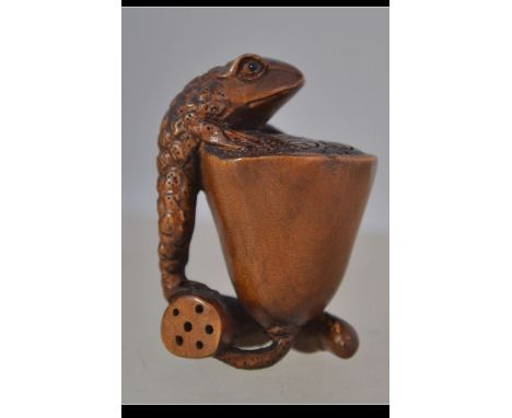 A carved fruit wood Japanese netsuke depicting a frog on a lotus leaf - flower bearing signature to underside