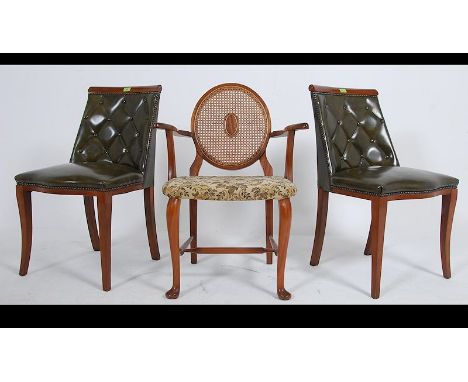 A pair of 20th century Chesterfield style club dining chairs with a green leather button back upholstery raised on sweeping s