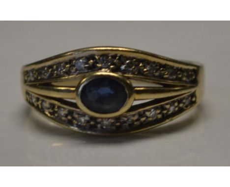 A 9ct gold sapphire and diamond ring set with a central oval cut sapphire with twin diamond set channels. Marked 9ct tests 9c