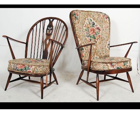 A pair of Ercol beech and elm wood Windsor pattern armchairs raised on turned legs with stretchers and cushions above. Matchi