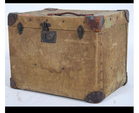 A vintage early 20th century Edwardian canvas and wood bound steamer trunk of square form with hinged lid and travel labels a