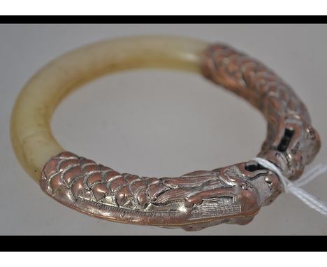 A Chinese jade mutton fat coloured bangle with copper twin headed dragon top