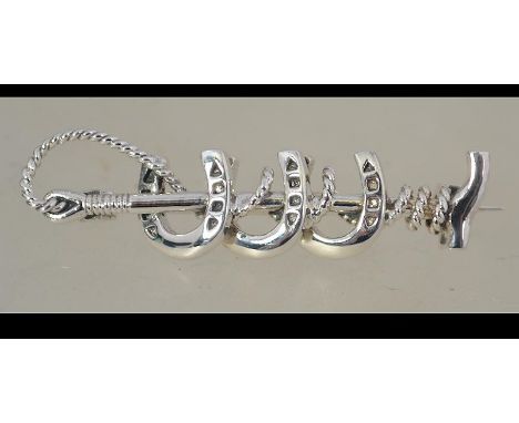 A silver horse - hunting brooch in the form of a riding crop and 3 horse shoes. Pin to verso Weight 4.5g / Size 4cms