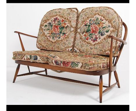 An Ercol beech and elm wood Windsor pattern two seat sofa settee raised on turned legs with stretchers and cushions above. Ma