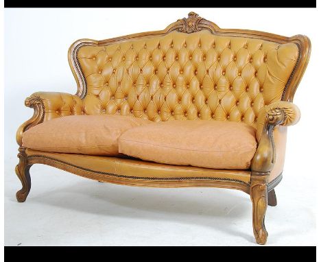 A 20th century rococo leather French sofa canape. The two seat sofa upholstered in mustard yellow leather set to a show wood 