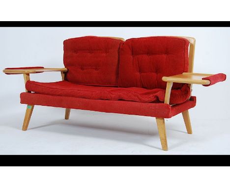 A 1950's retro mid century two seat sofa settee raised on tapered legs with unusual table elbow rests, Upholstered in a red f