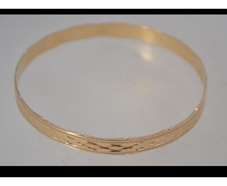 A hallmarked 9ct gold bangle with scalloped edges and diamond cut star engraving. Hallmarked London. Weight 10g