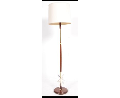 A retro 20th century teak and brass ring column standard lamp supported on a circular base with shade. Measures: 152cms high.