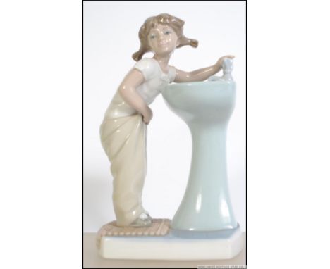 A Lladro ceramic figurine entitled ' Clean up time '. The figurine of girl at sink in towel. stamped to the base with Lladro 