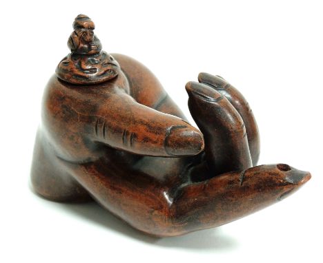An earthenware oil lamp taking the form of a partially open hand with outstretched finger,  the finial moulded as a mythical 