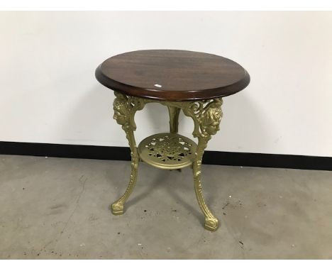 A vintage café table, cast iron gilt painted base with circular wooden top, 58cm diameter x 70cm high 