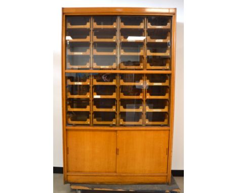 A 1930's oak haberdasher's cabinet, fitted interior with 32 comb jointed drawers, four sliding glass doors and two cupboards 