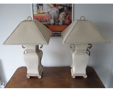 A pair of contemporary ceramic table lamps, simulated stone effect with scroll feet and handles, together with cream shades, 