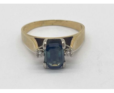 A Diamond Set Dress Ring, the teal coloured centre stone of emerald cut, between brilliant cut diamond shoulders and wide tap