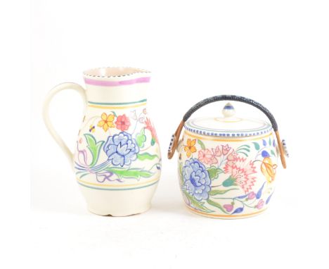 A Poole Pottery biscuit barrel, floral decoration, cane handle, 15cm; and a Poole jug. (2)