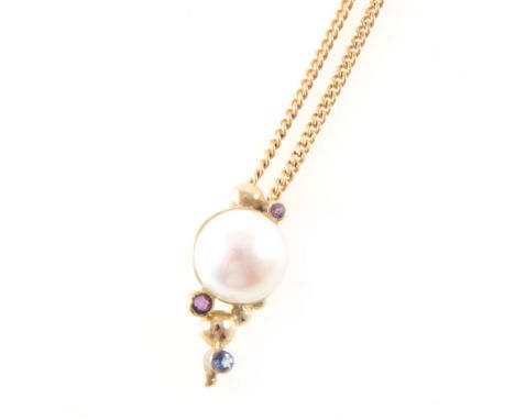 A modern yellow metal pendant set with a 12mm Mabe pearl with closed back setting, two small amethysts and a sapphire on a 9 