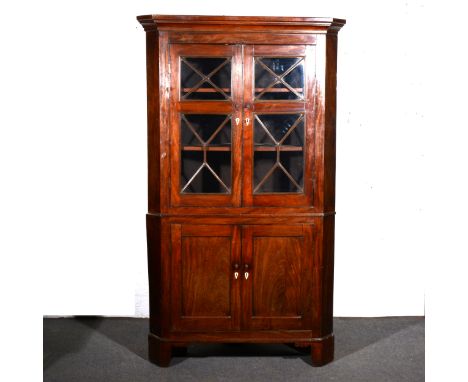 A George III mahogany free-standing corner cupboard, moulded cornice, the upper section with glazed doors, enclosing two fixe