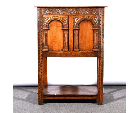 A reproduction oak cabinet, carved decoration, two doors with arcading, open shelf under, width 68cm.