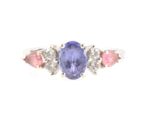 A tanzanite and diamond ring, the oval mixed cut tanzanite 7mm x 5mm four claw set with two brilliant cut diamonds to each si