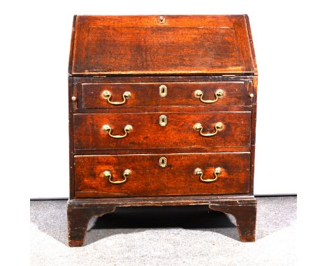 George III oak bureau, of small size, fall front enclosing a part fitted interior with drawers and pigeon holes, three long d