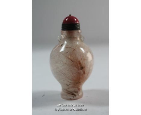 A Chinese pink stone snuff bottle with red stone finial.