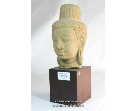 A Cambodian carved stone head, mounted on a wooden stand, 26.5cm overall.