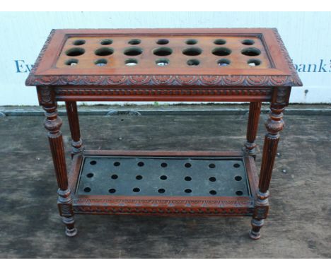 An Edwardian mahogany stick stand, with foliate carved frieze.  The top with twenty one circular divisions, raised on fluted 