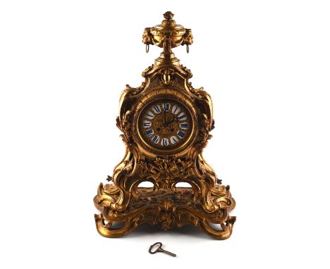 A large and impressive French ormolu mantle clock, cast with an urn finial , musical trophy's and scrolling foliage, on a nat