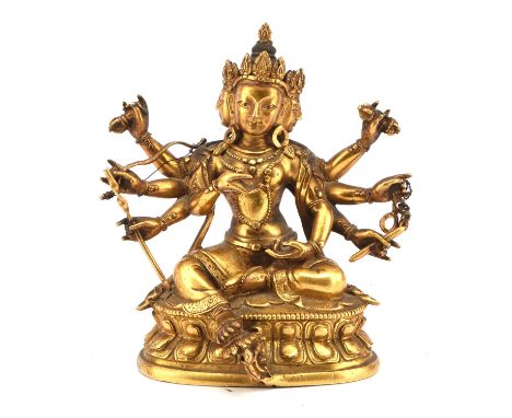 A gilded metal figure of a Buddhist Deity with four faces and eight hands; the principal hands expressed in mudra and the rem