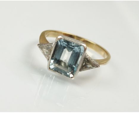 An aquamarine and diamond set ring, designed as central rectangular step cut aquamarine, flanked to each side by a triangular