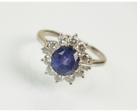 An 18ct white gold sapphire and diamond cluster ring, designed as a central oval mixed cut sapphire within a border of eight 