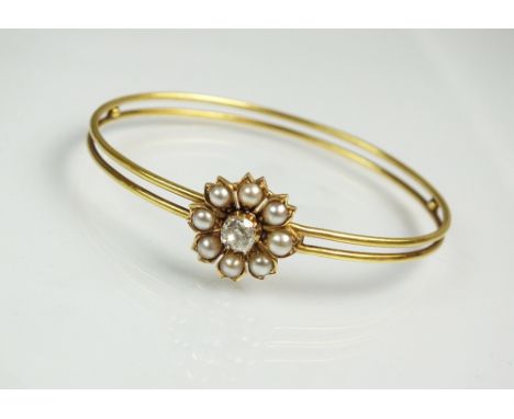 A late 19th century diamond and pearl bangle, designed as an old cut diamond and half pearl floral cluster set to openwork ye